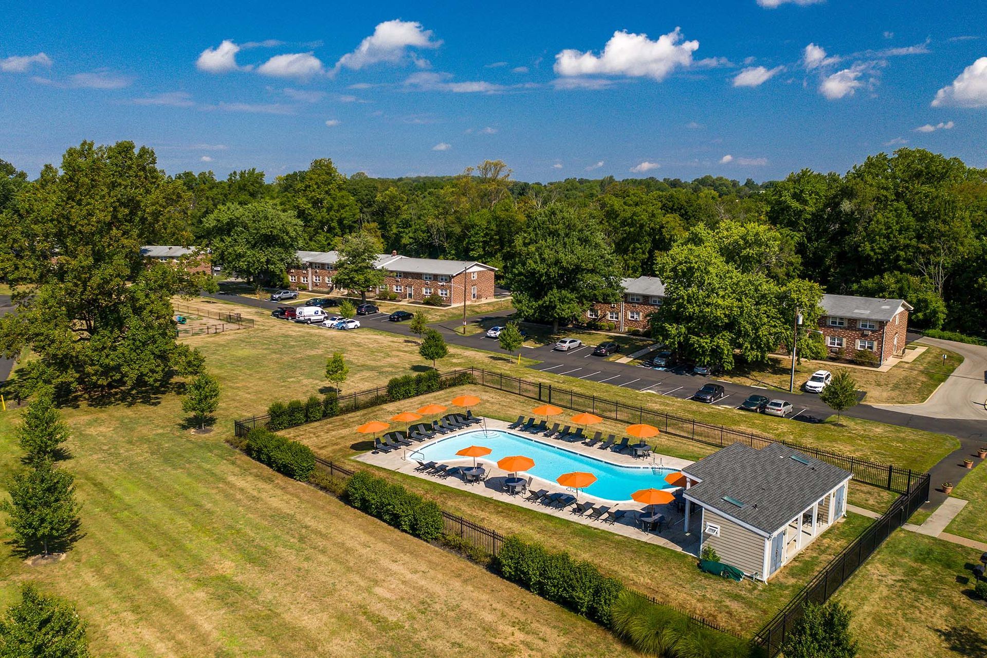 Aerial view of a residential pool area with orange umbrellas and surrounding buildings.