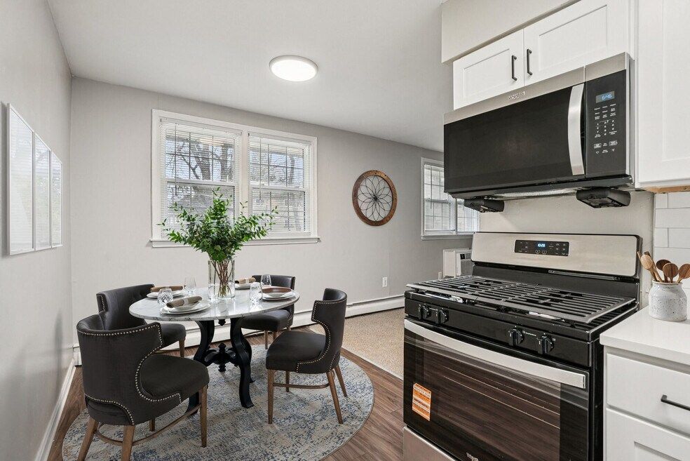 Kitchen and dining area with a round table, chairs, and appliances.