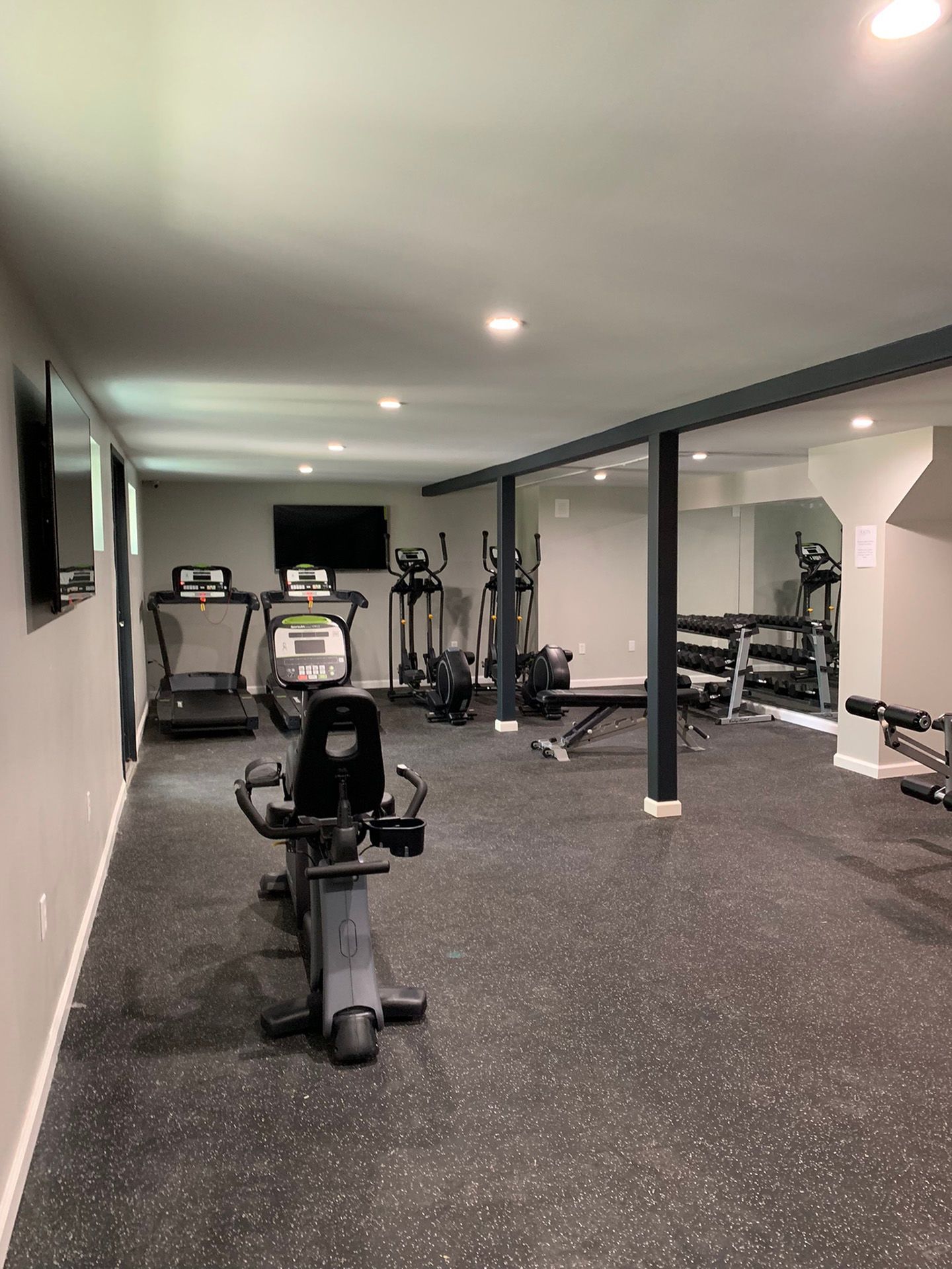 Indoor resident fitness center with treadmills, ellipticals, and weight benches.