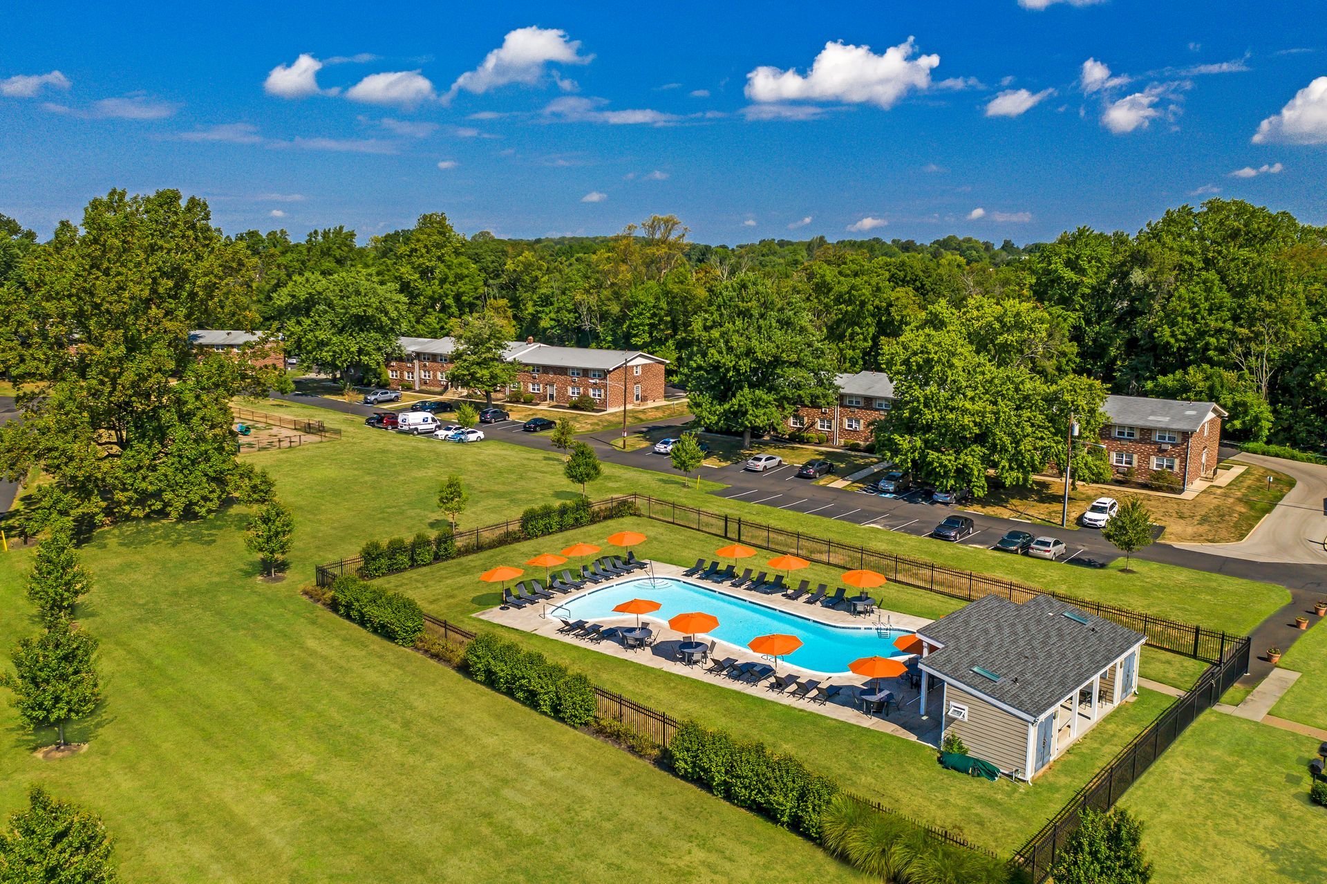 Aerial view of apartment complex with pool and surrounding green lawn.