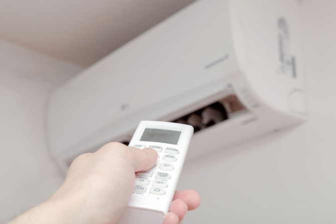 A white air conditioner is sitting on the side of a building.