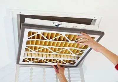 A person is changing a filter on a ceiling fan.