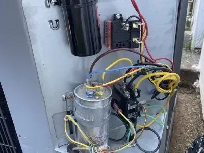 The inside of a refrigerator with a lot of wires coming out of it.
