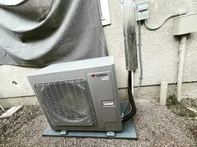 A large air conditioner is sitting outside of a building.
