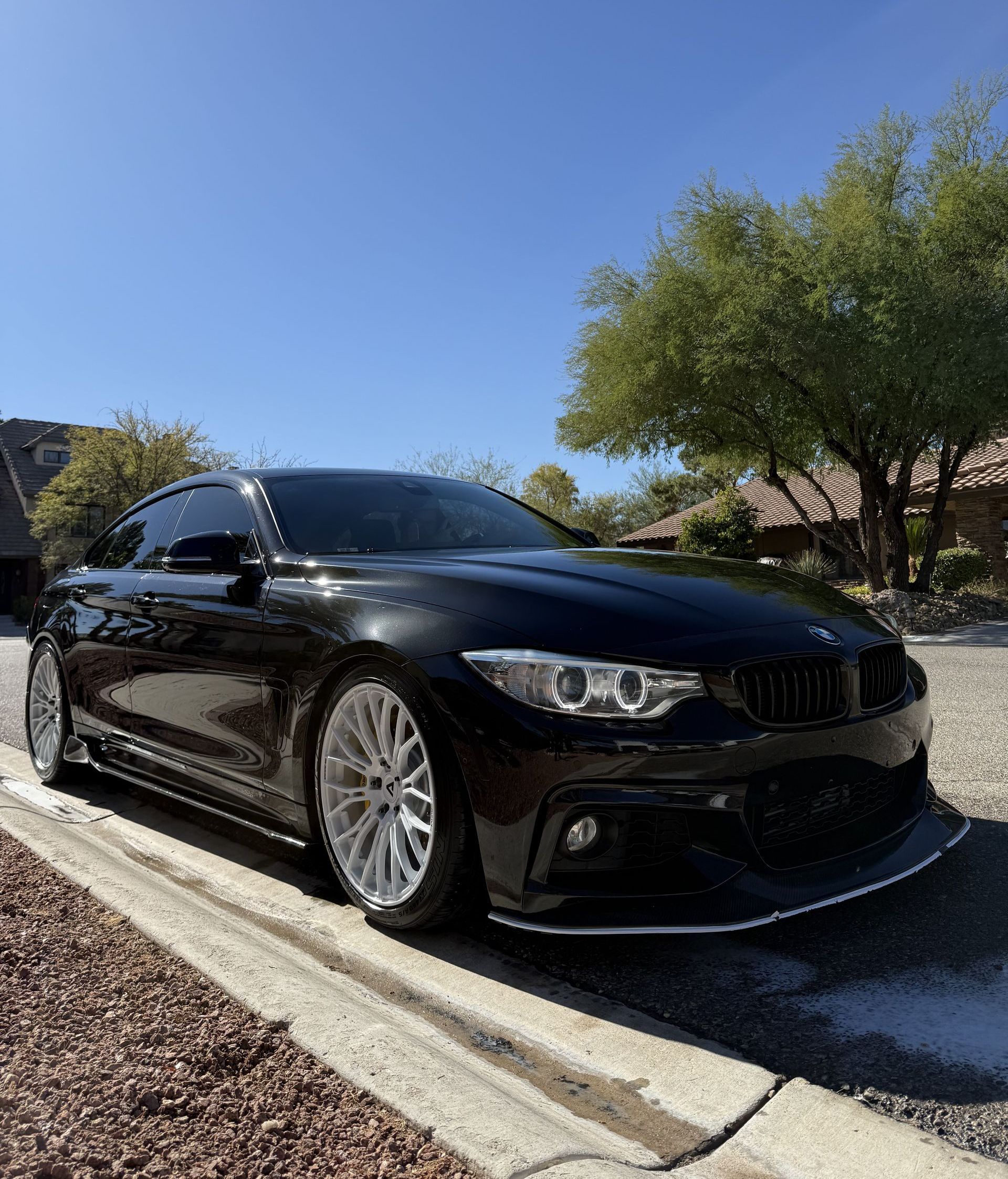 A black bmw is parked on the side of the road.