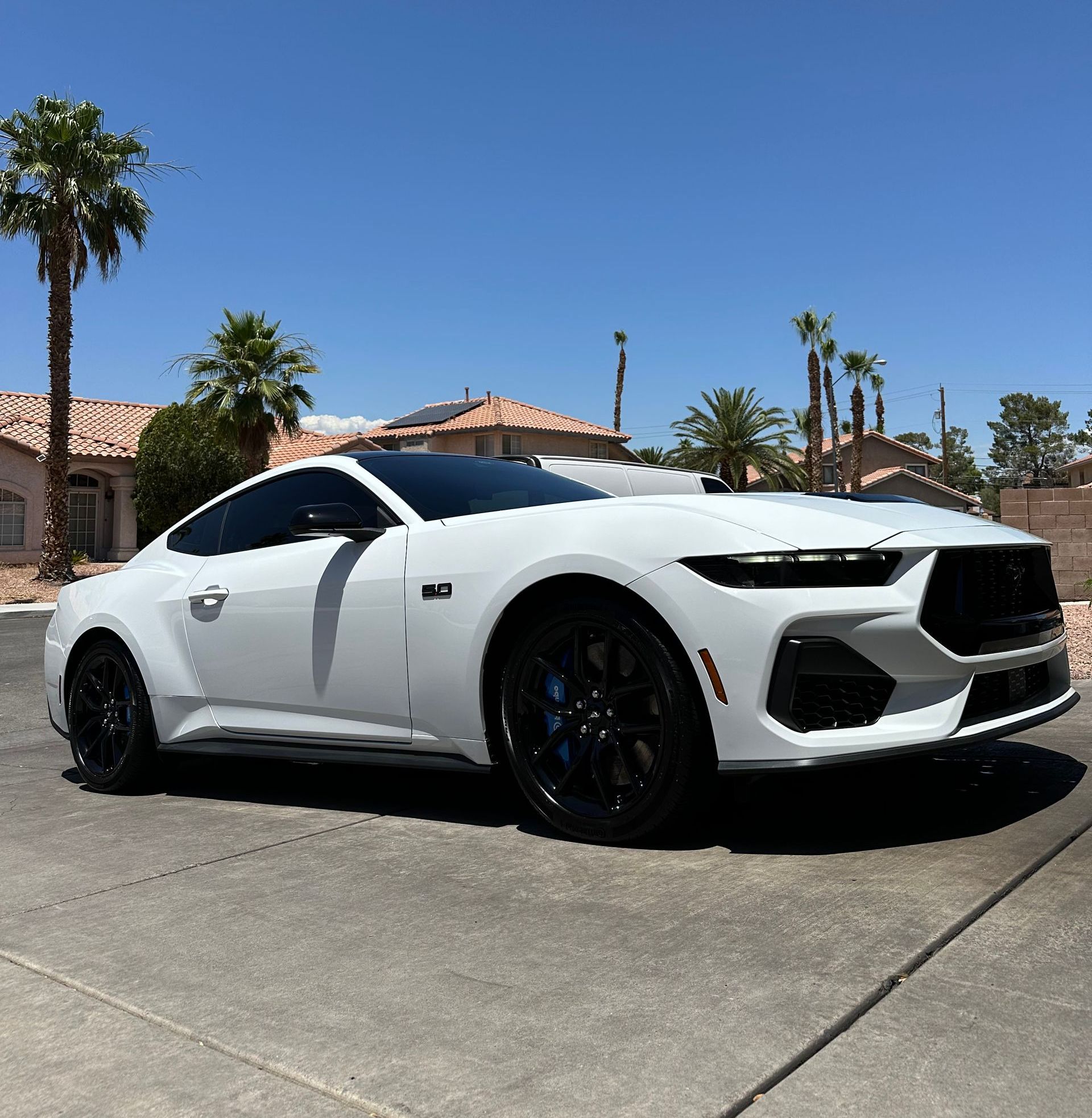 A white sports car is parked on the side of the road.