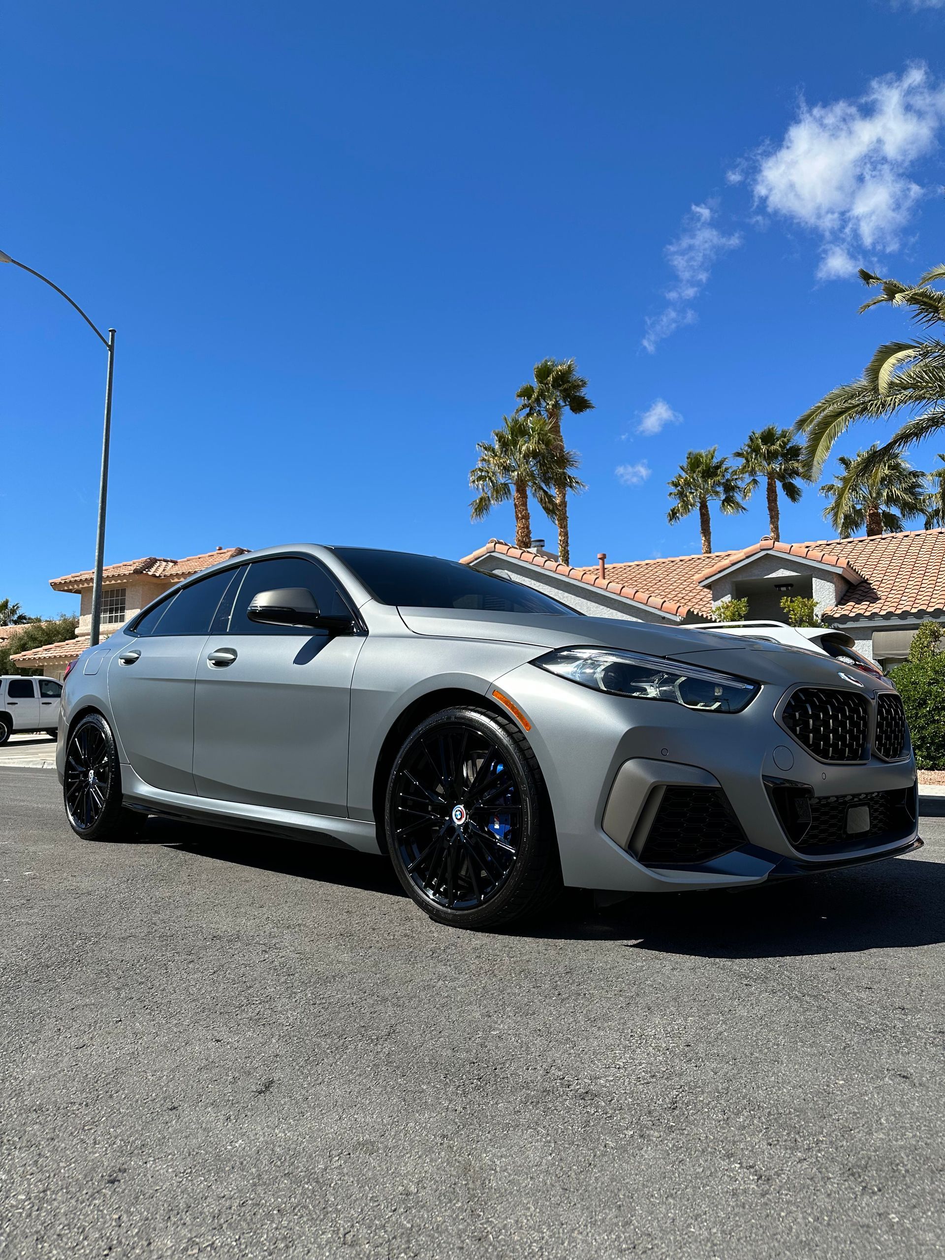 A bmw m4 is parked on the side of the road next to a van.