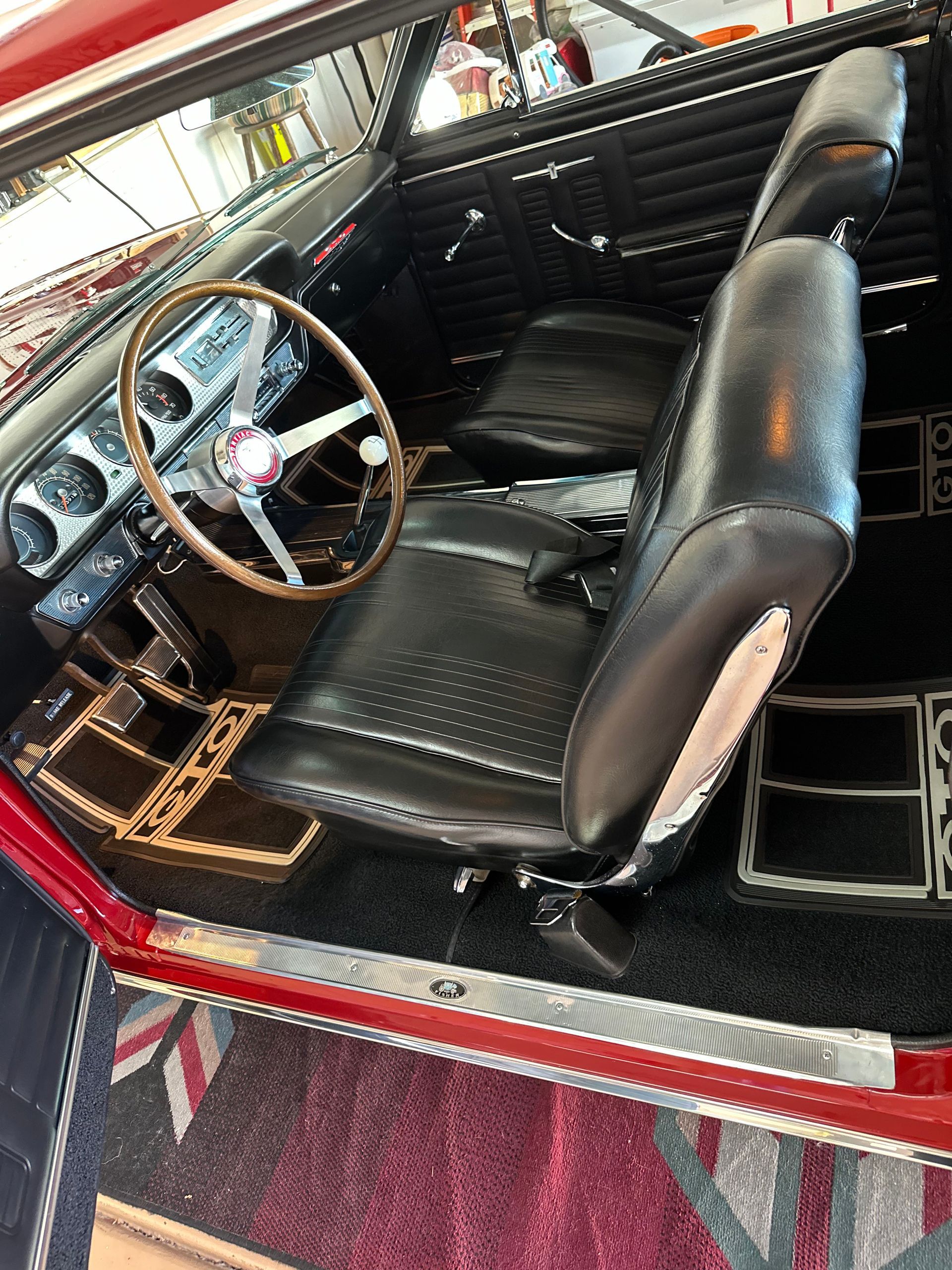 The interior of a red car with black seats and a steering wheel.