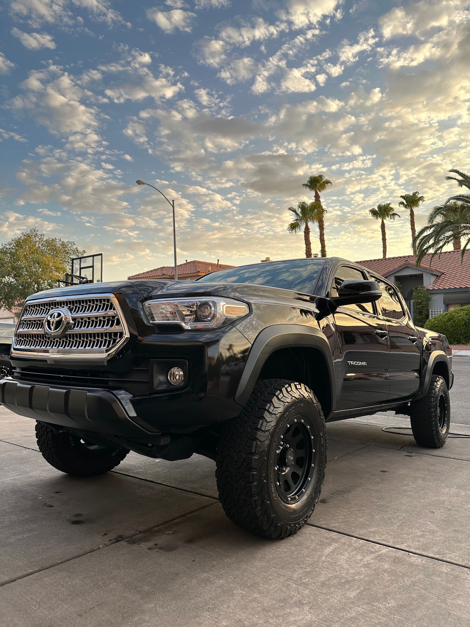 A black toyota tacoma truck is parked on the side of the road.