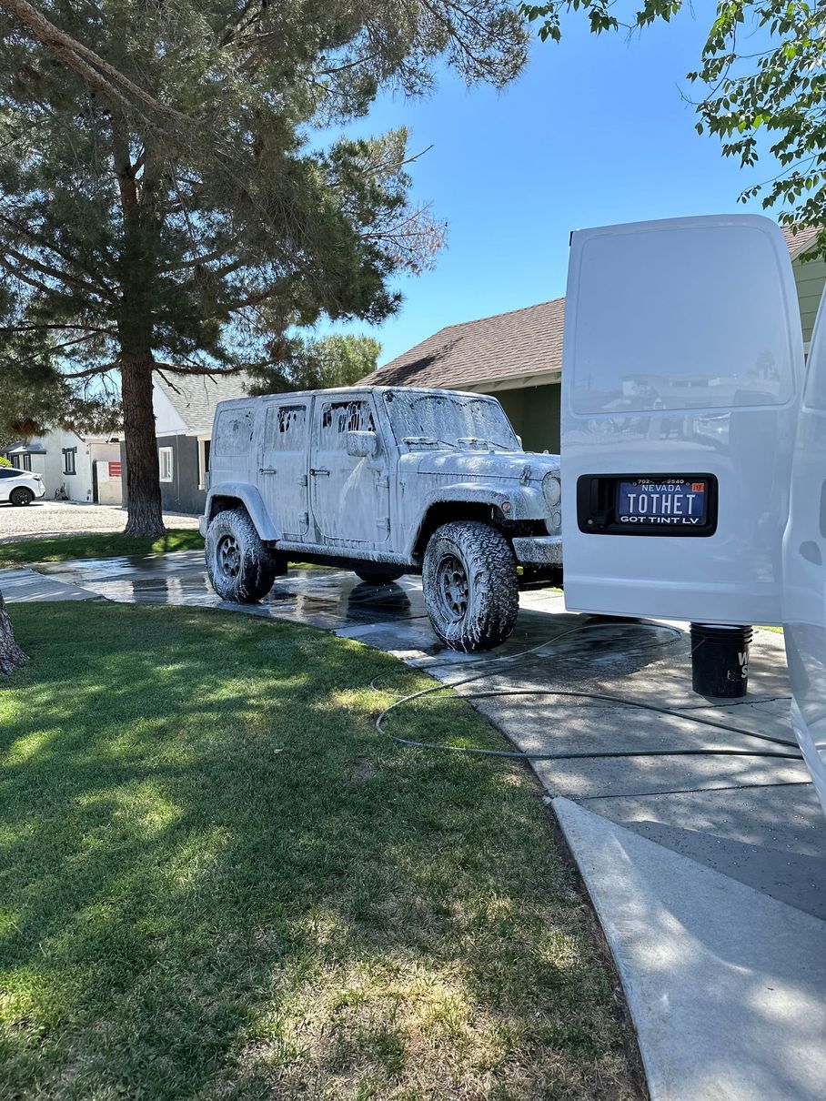 A white van is parked next to a jeep covered in foam.