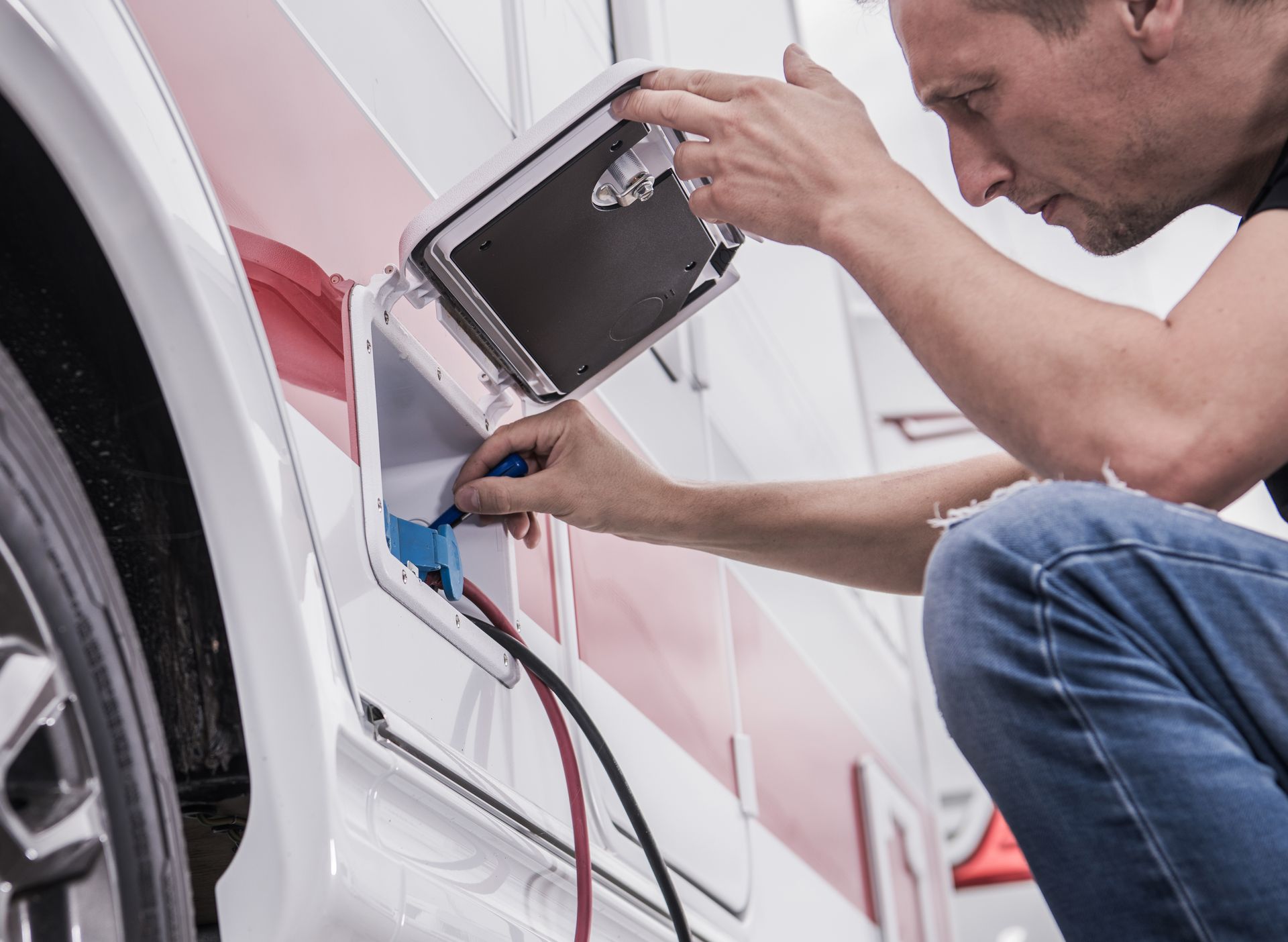 Mechanic using a power tool to repair the side of a white car