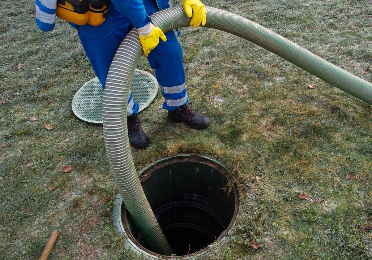 A man is pumping water into a septic tank with a hose.