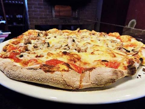 A pizza with tomatoes and cheese on a white plate