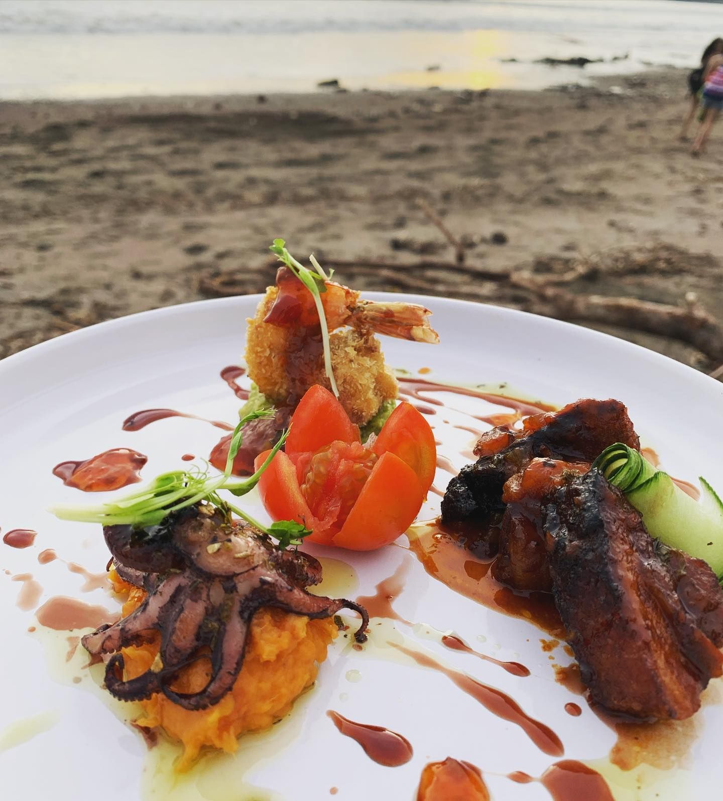 A plate of food on a beach with a person in the background