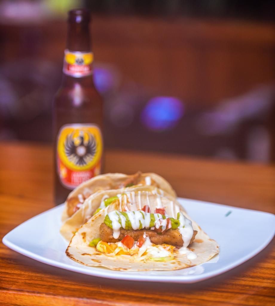 A plate of food with a bottle of beer in the background.
