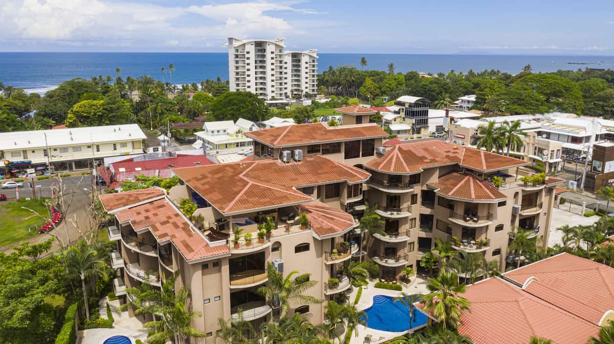 An aerial view of a large building with a pool in the middle of a city.