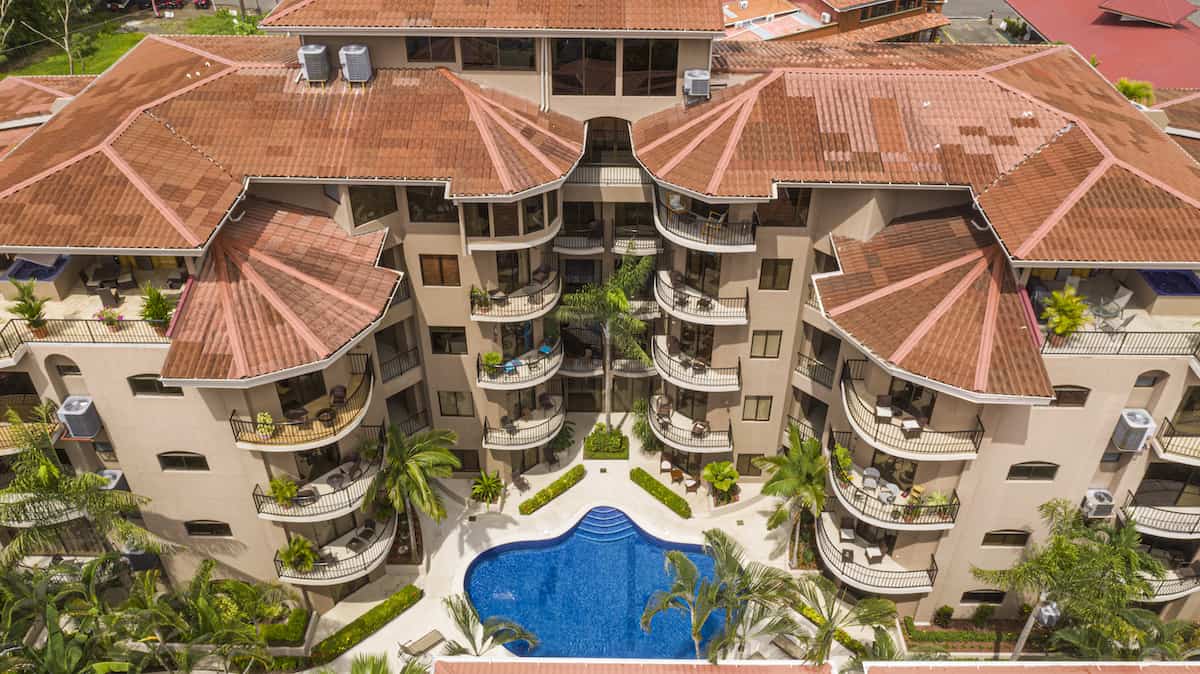 An aerial view of a large building with a pool in front of it.