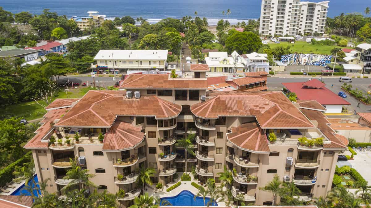 An aerial view of a large apartment building with a pool in front of it.