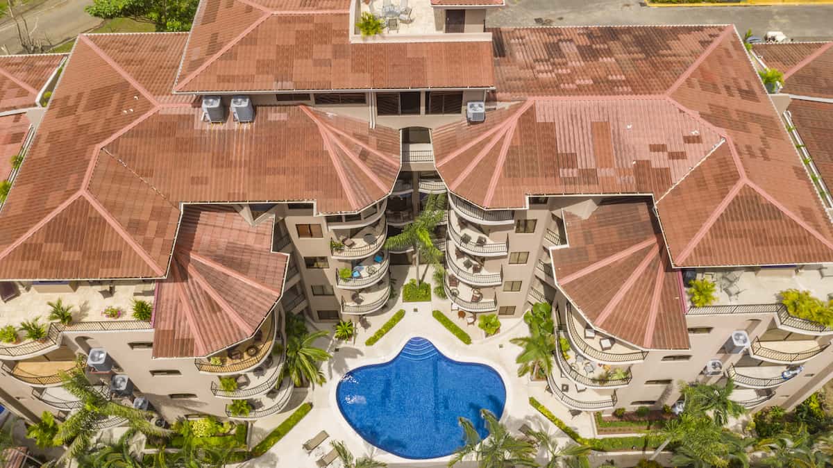 An aerial view of a large building with a swimming pool in front of it.