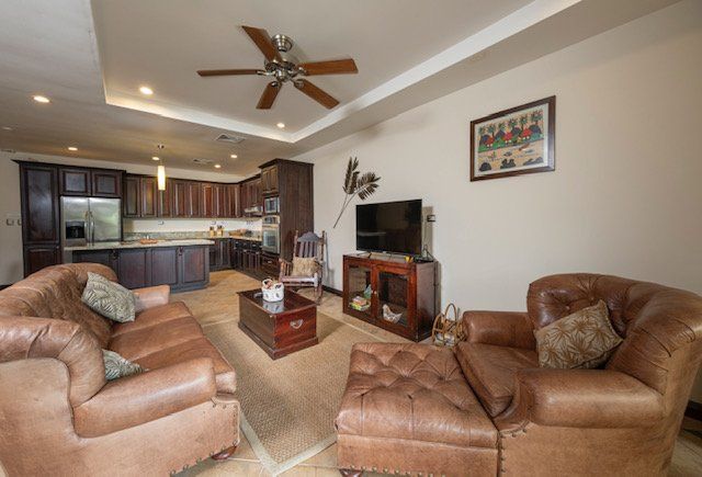 A living room with brown furniture and a ceiling fan