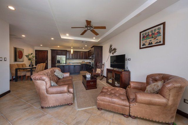 A living room with brown furniture and a ceiling fan