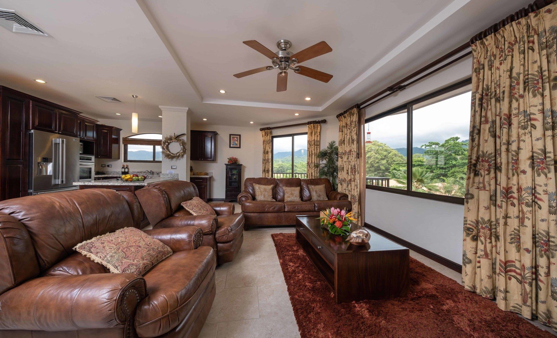 A living room with brown furniture and a ceiling fan