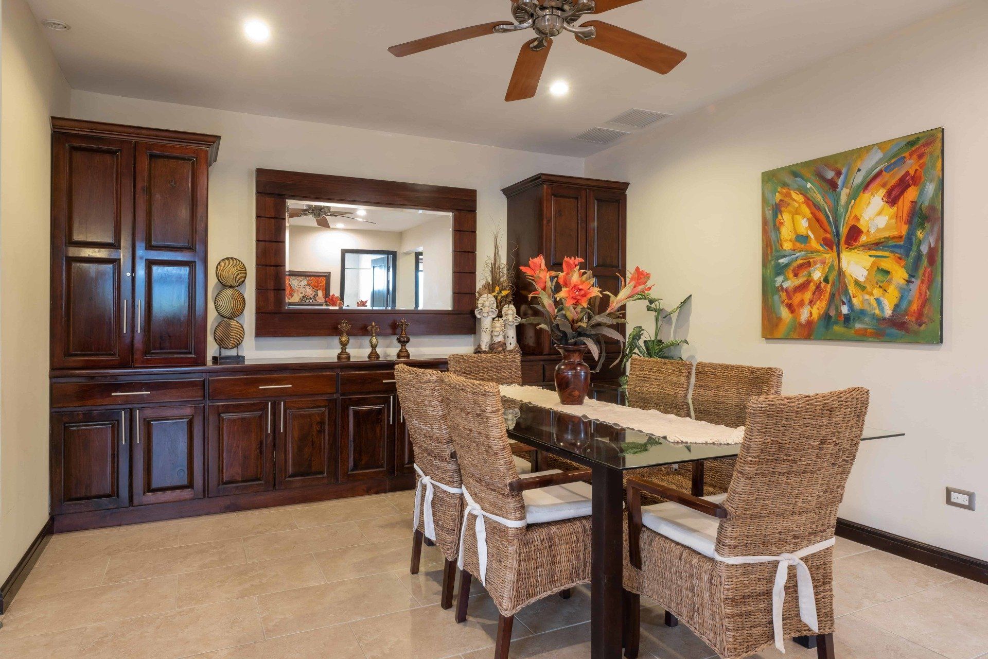 A dining room with wicker chairs and a ceiling fan