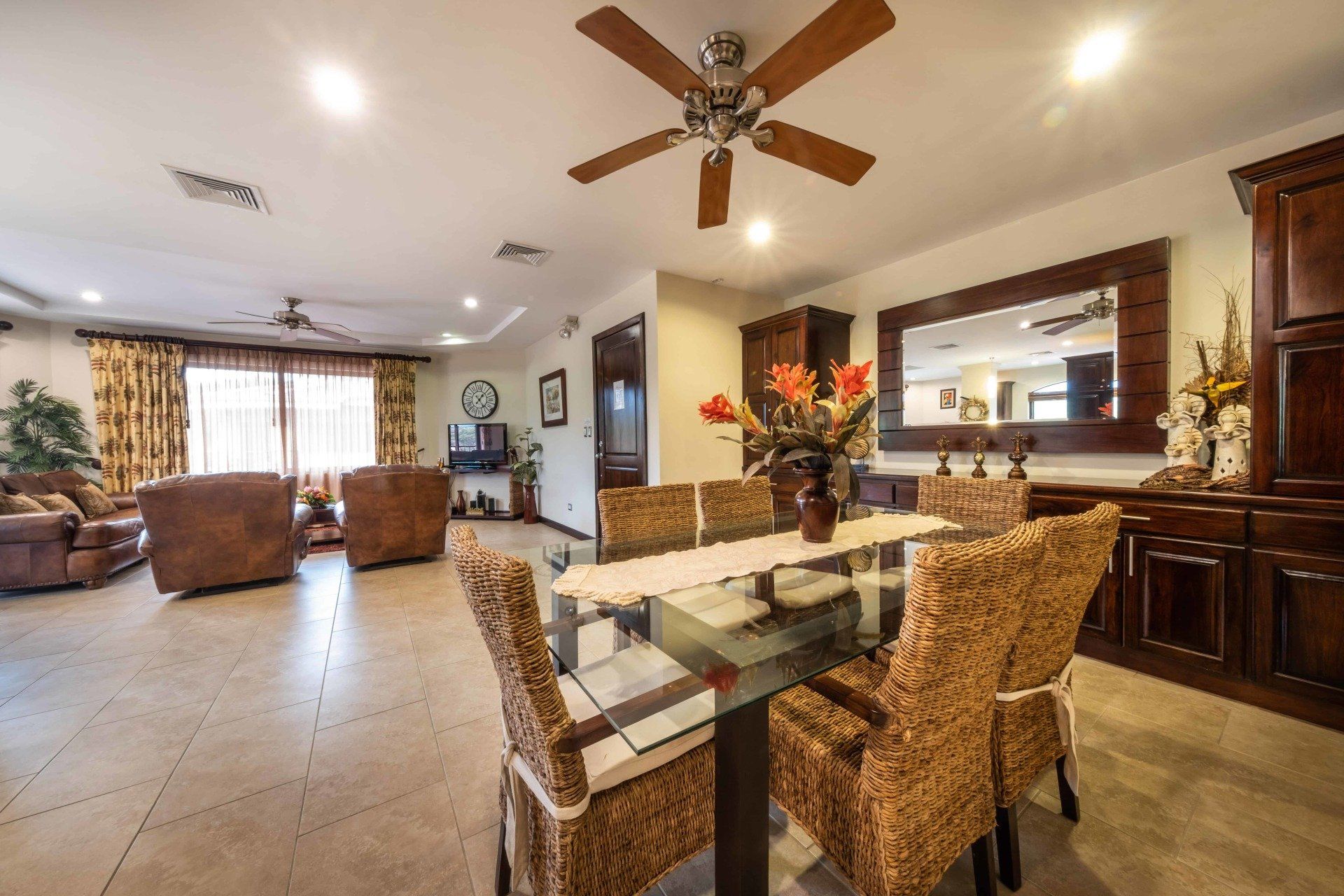 A living room with a dining table and chairs and a ceiling fan.