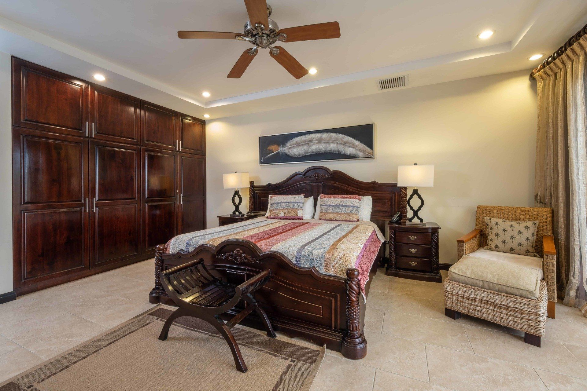 A bedroom with a large bed and a ceiling fan