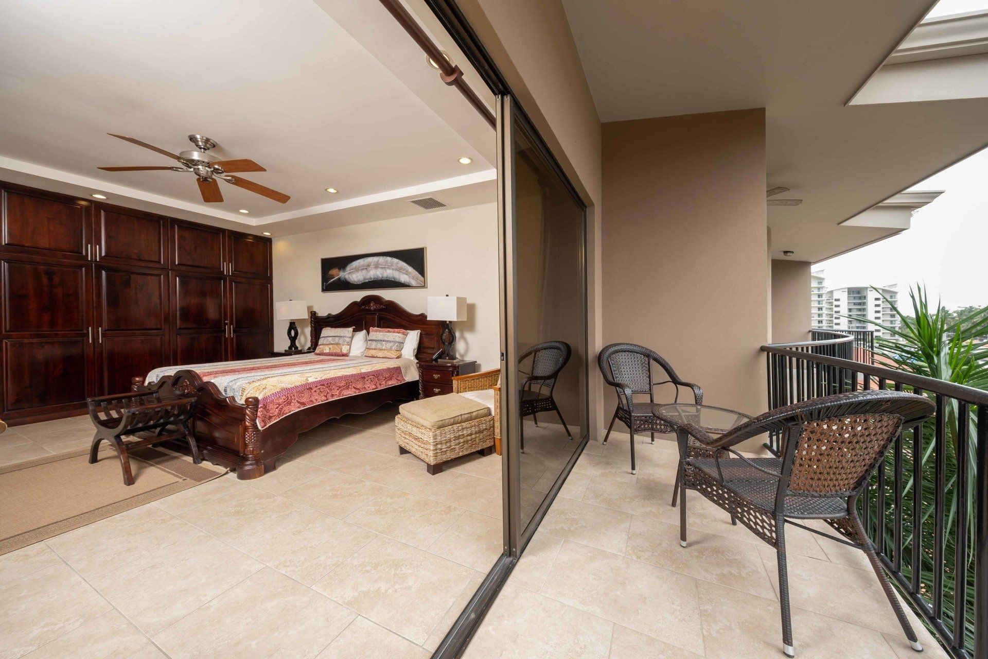 A bedroom with a large bed and a balcony with chairs