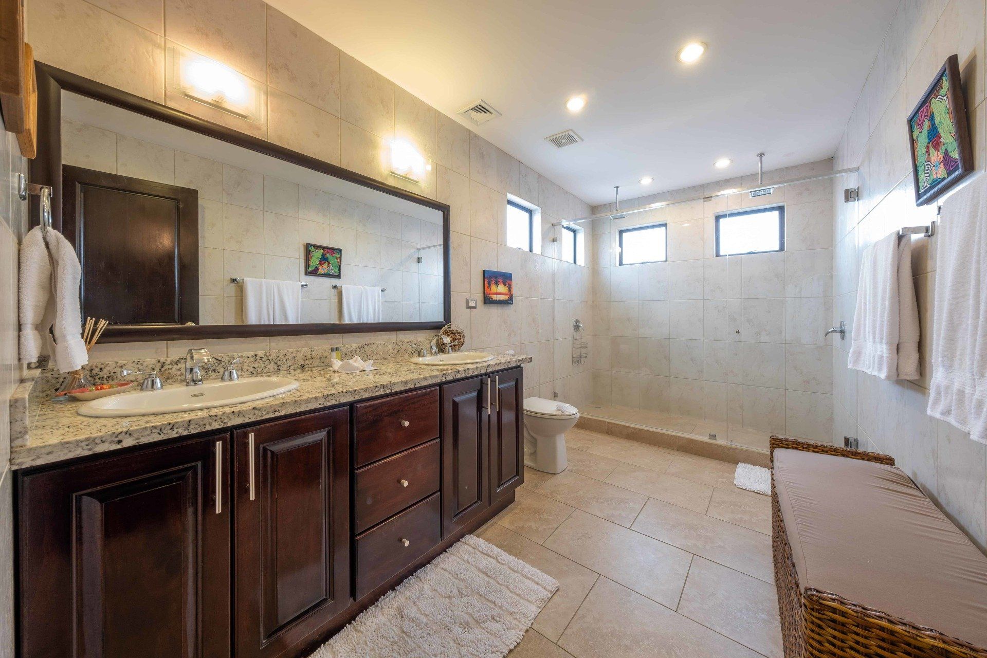 A bathroom with two sinks , a large mirror and a walk in shower.