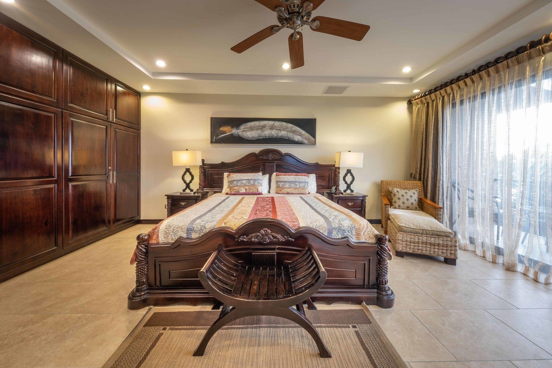 A bedroom with a large bed and a ceiling fan