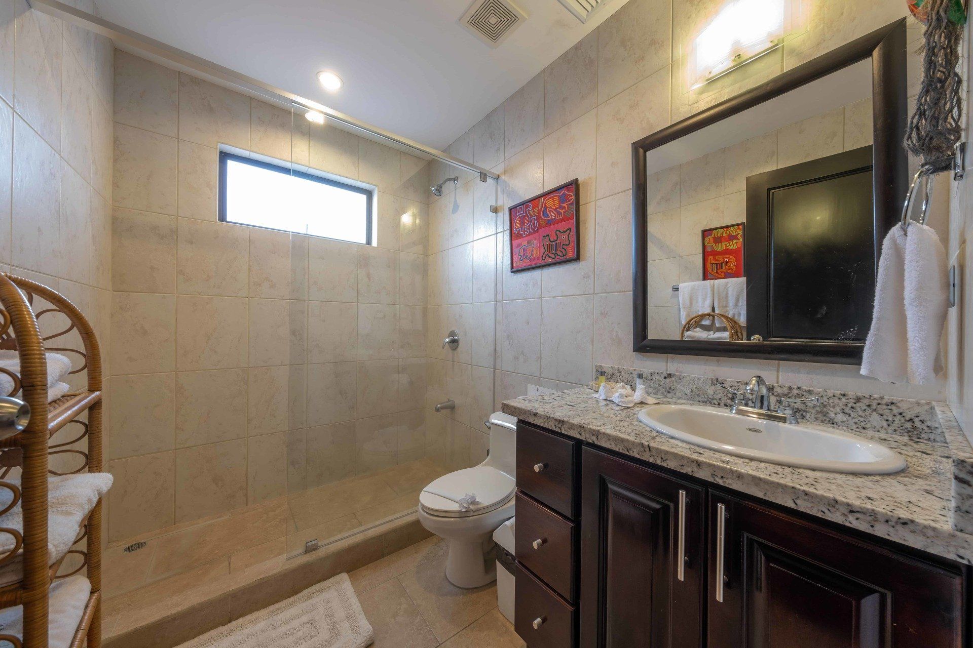 A bathroom with a toilet , sink , mirror and walk in shower.