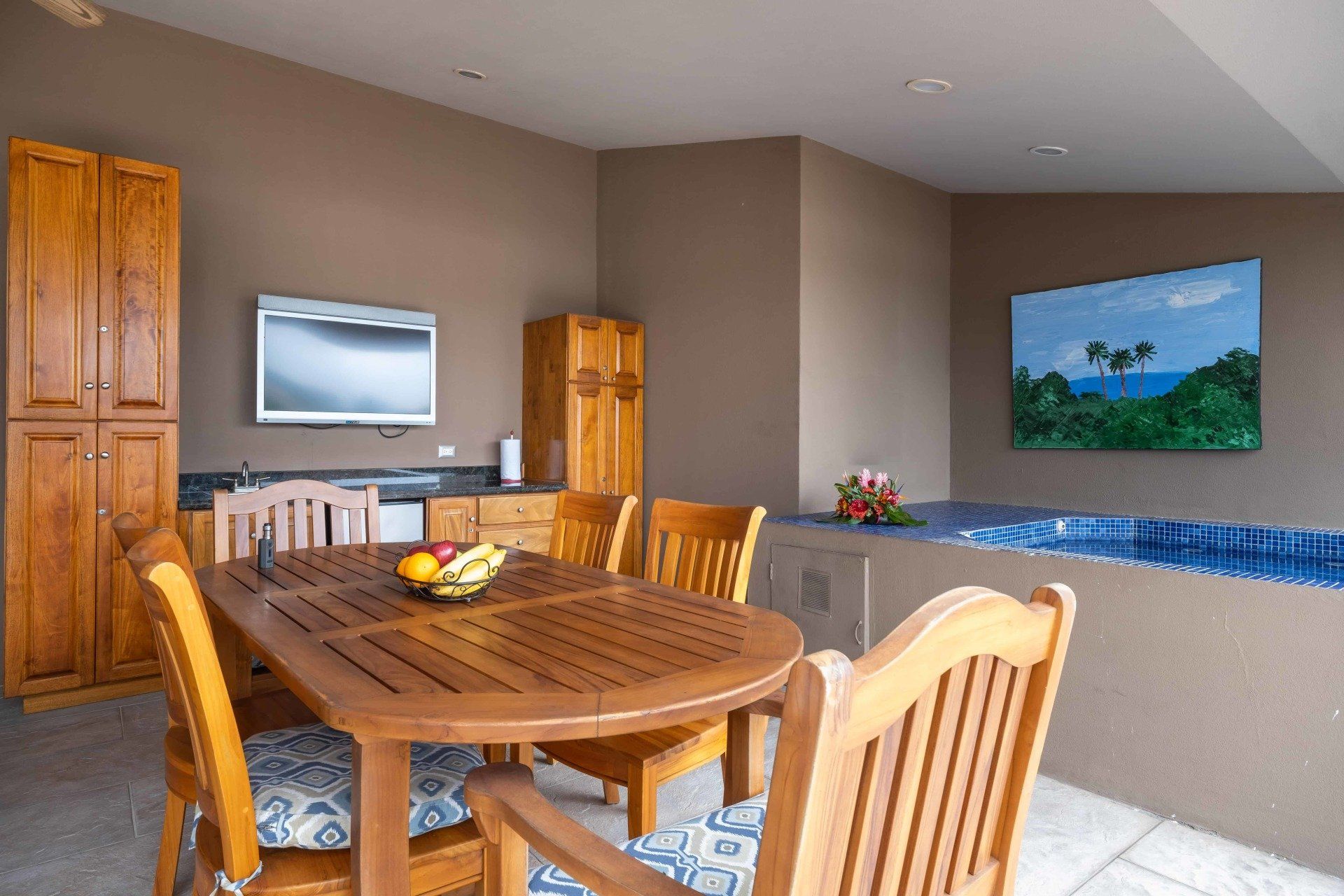 A dining room with a table and chairs and a flat screen tv