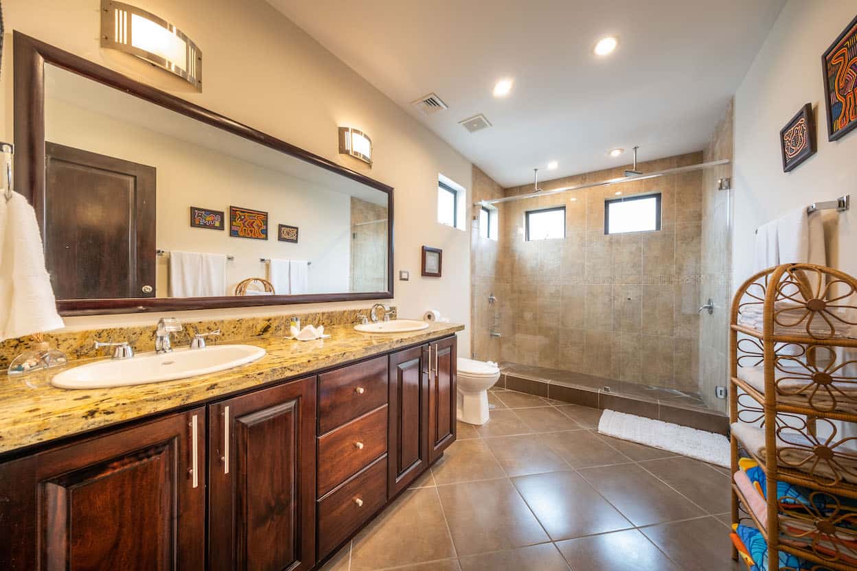 A bathroom with two sinks , a toilet , and a large mirror.