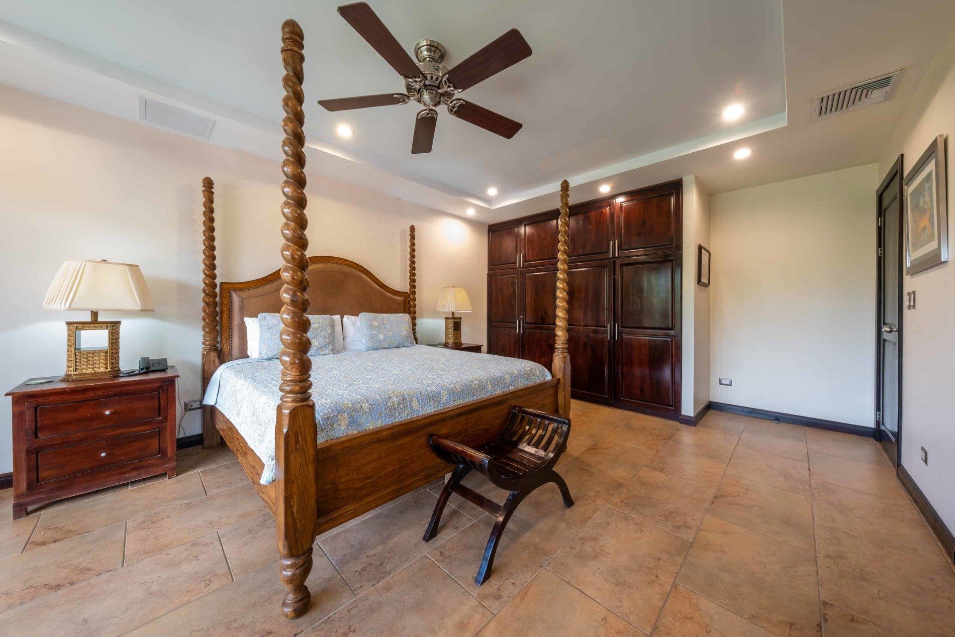 A bedroom with a four poster bed and a ceiling fan.