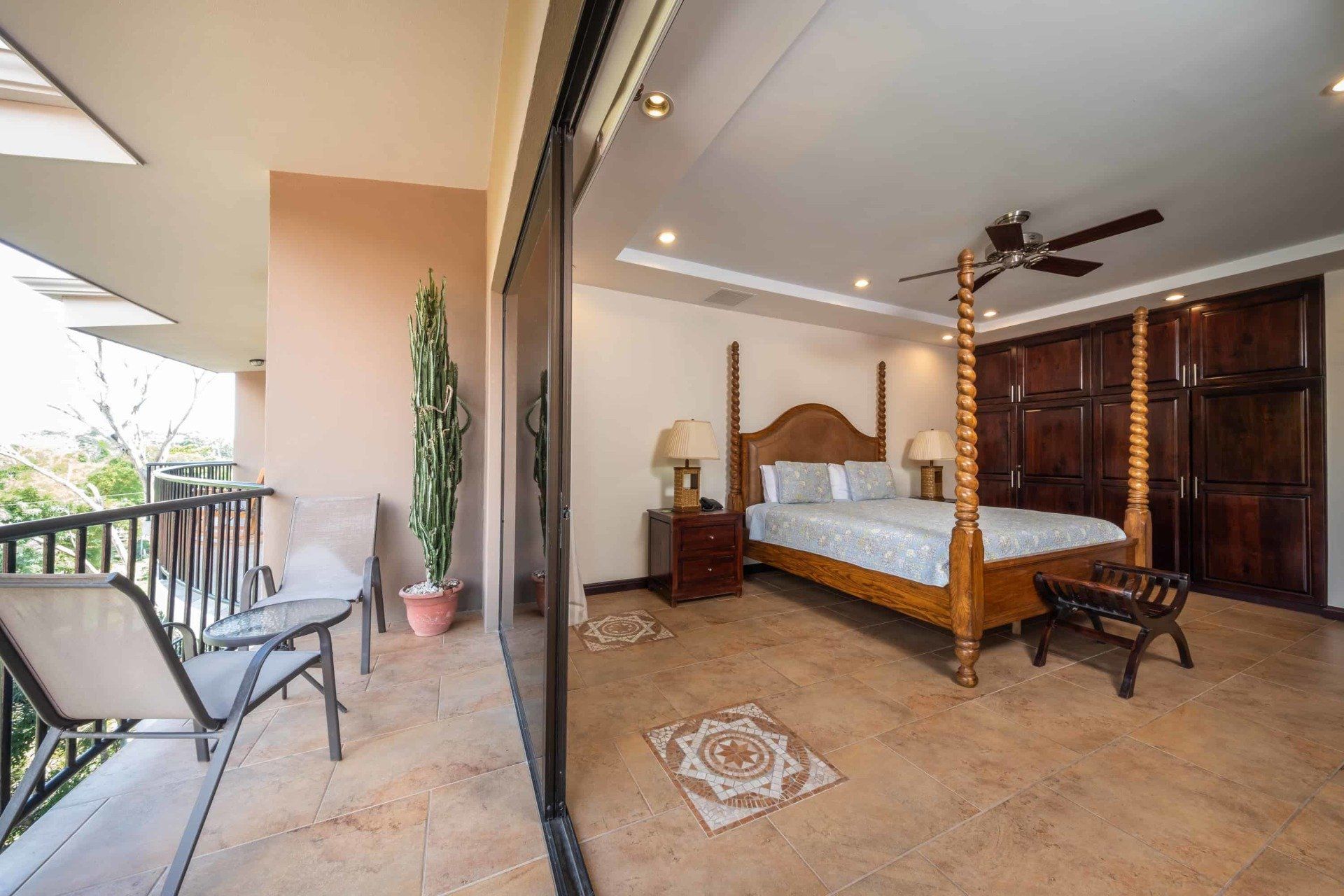 A large bedroom with a four poster bed and a balcony.