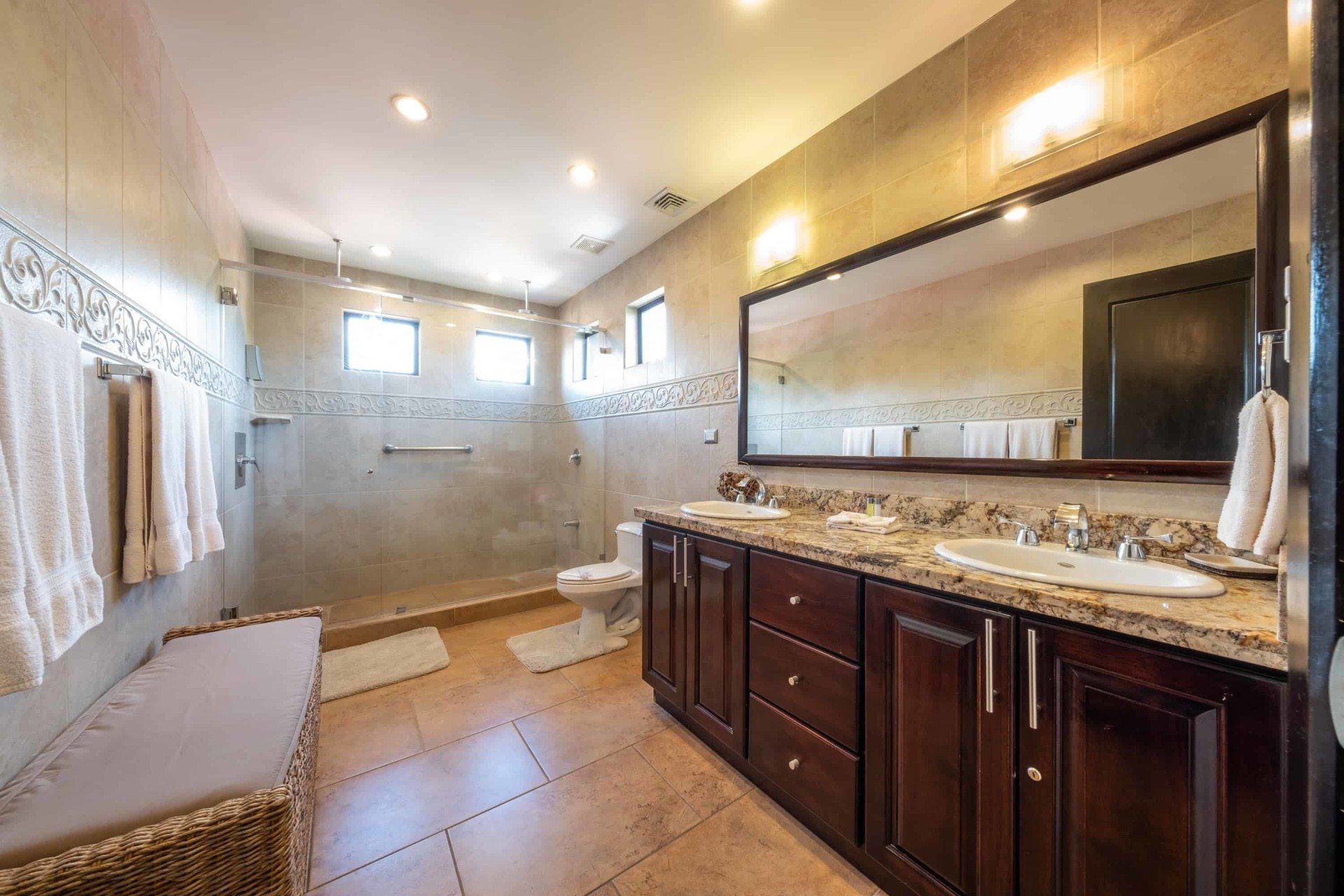 A bathroom with two sinks , a toilet , and a large mirror.