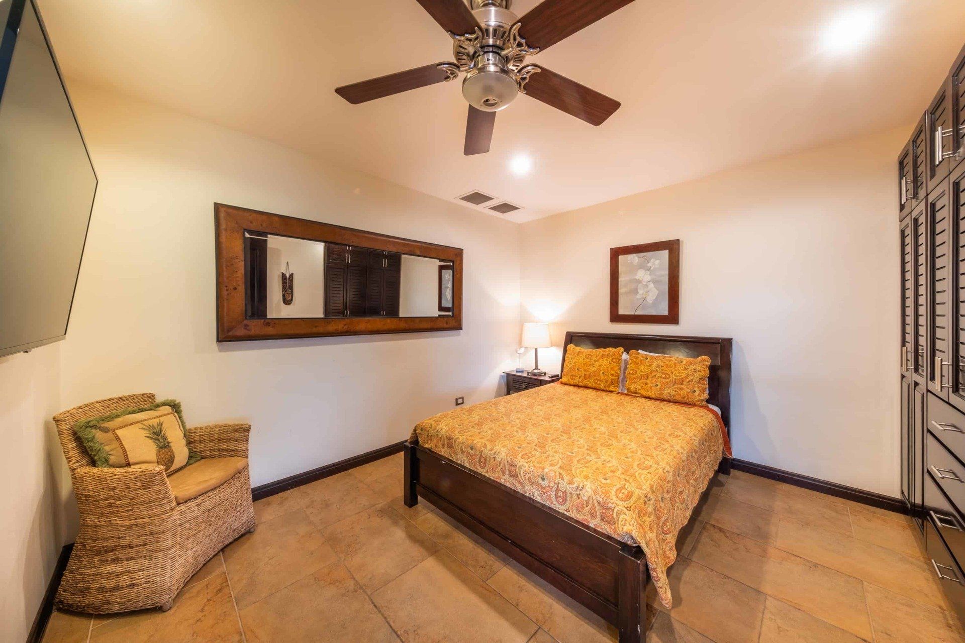 A bedroom with a bed , chair and ceiling fan.
