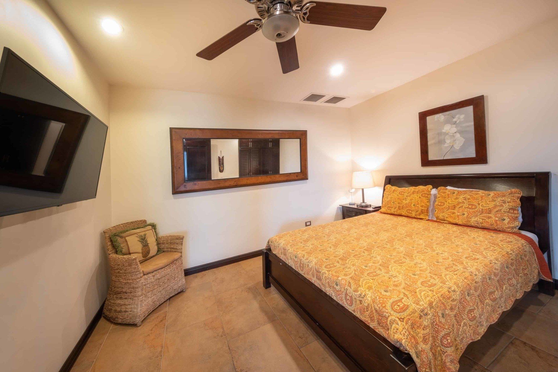A bedroom with a king size bed , chair and ceiling fan.