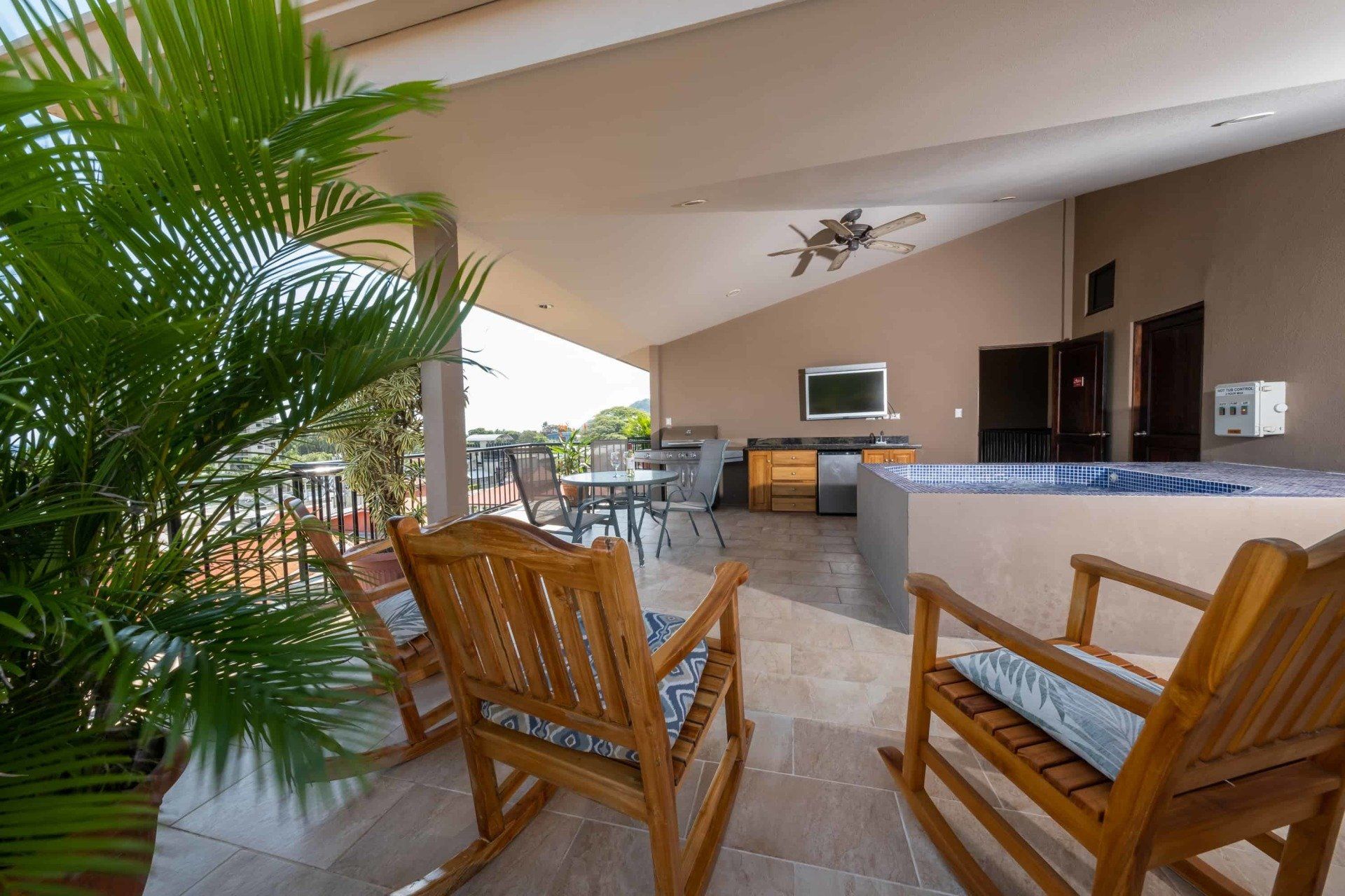Two wooden rocking chairs are sitting on a patio next to a palm tree.