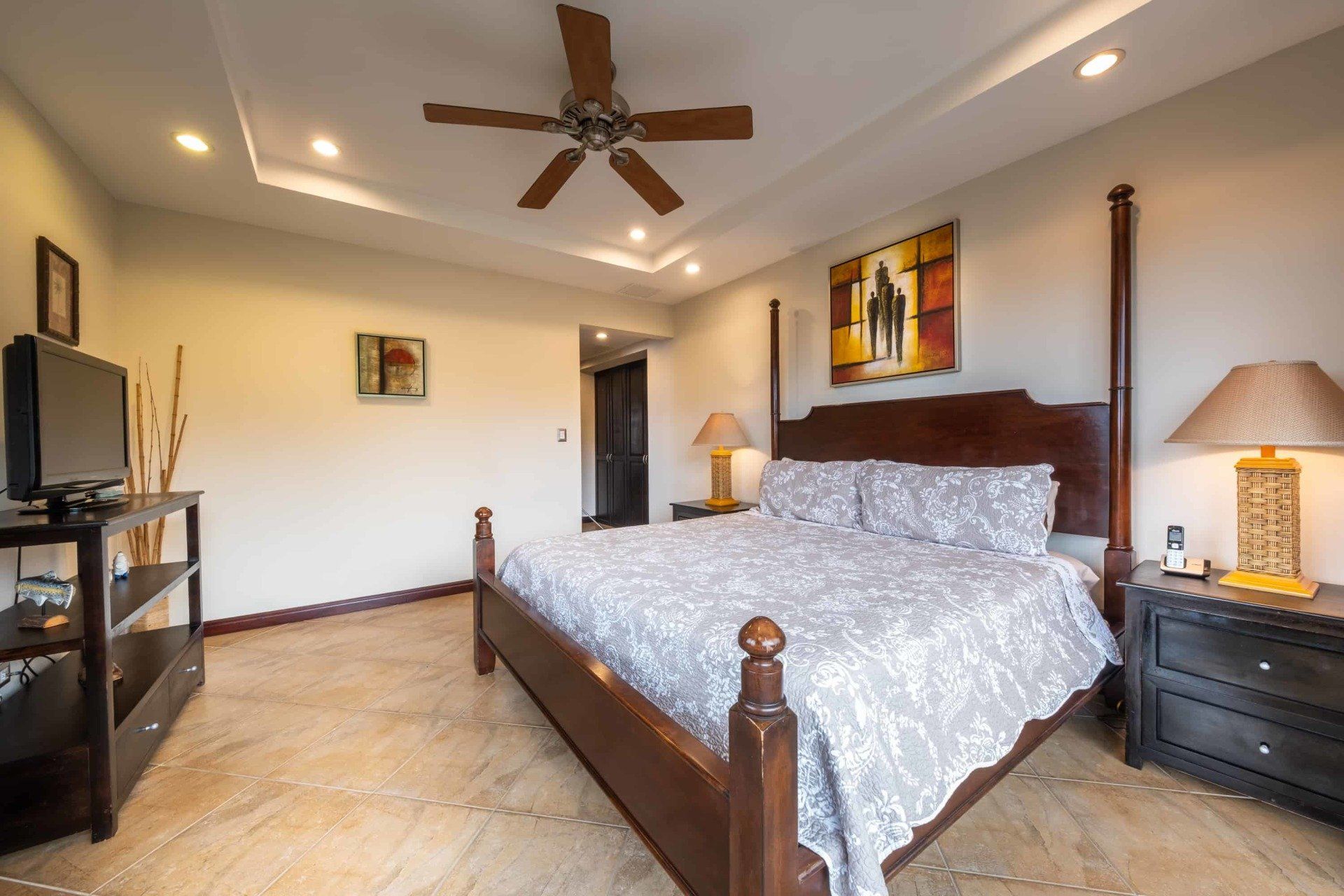 A bedroom with a king size bed and a ceiling fan