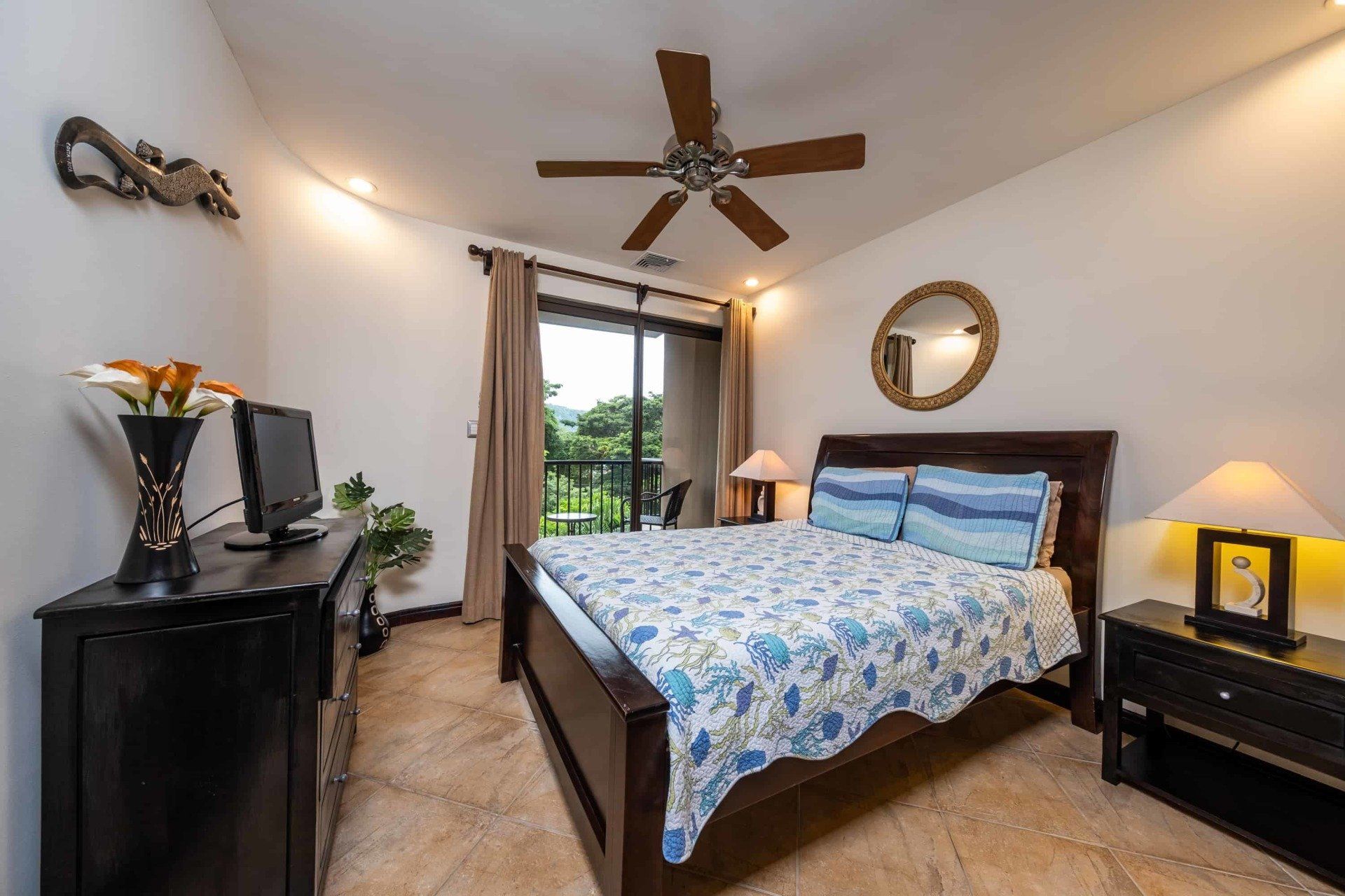 A bedroom with a large bed and a ceiling fan