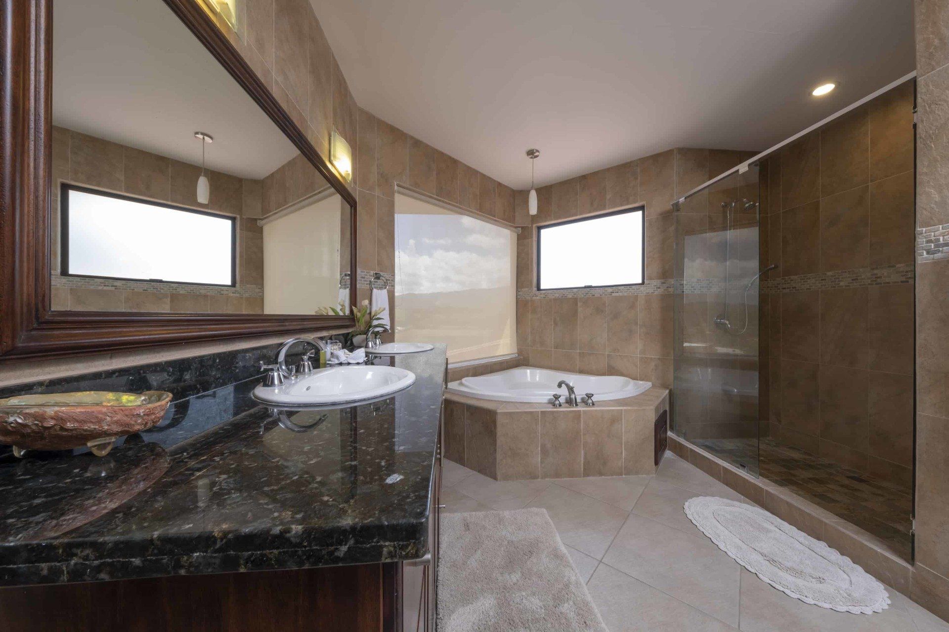 A bathroom with two sinks , a tub and a walk in shower.