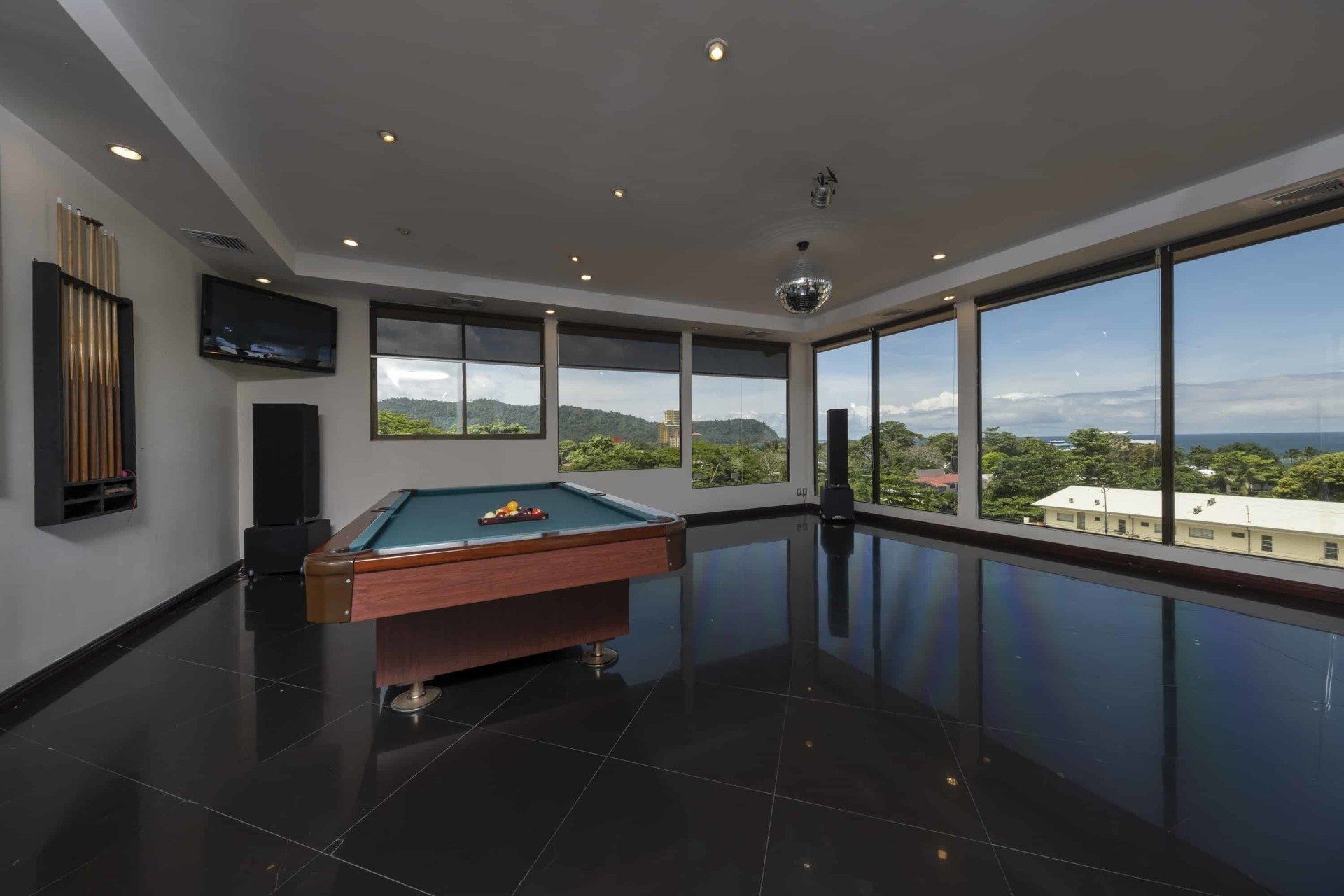 A pool table in a large room with lots of windows