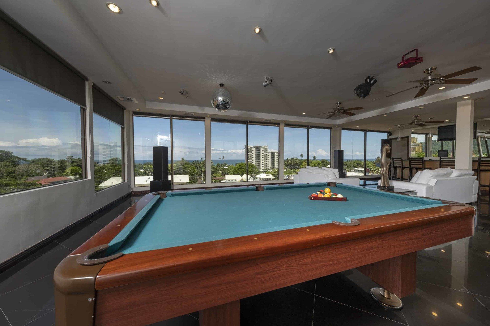 A pool table in a large room with lots of windows