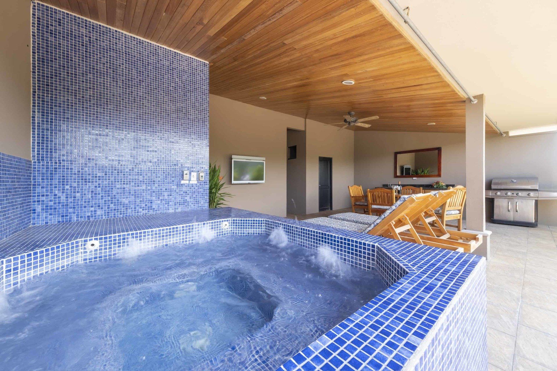 A jacuzzi with blue tiles and a television on the wall