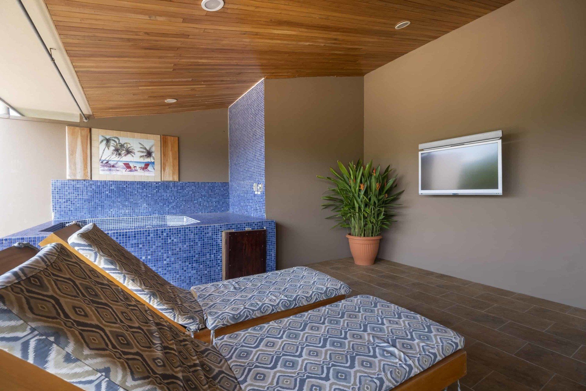 A room with two lounge chairs and a television on the wall.