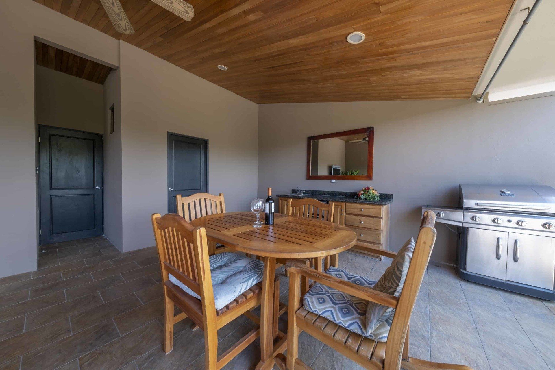 A patio with a table and chairs and a grill.