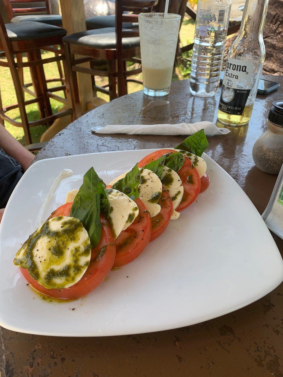 A white plate topped with tomatoes , mozzarella and basil on a table.